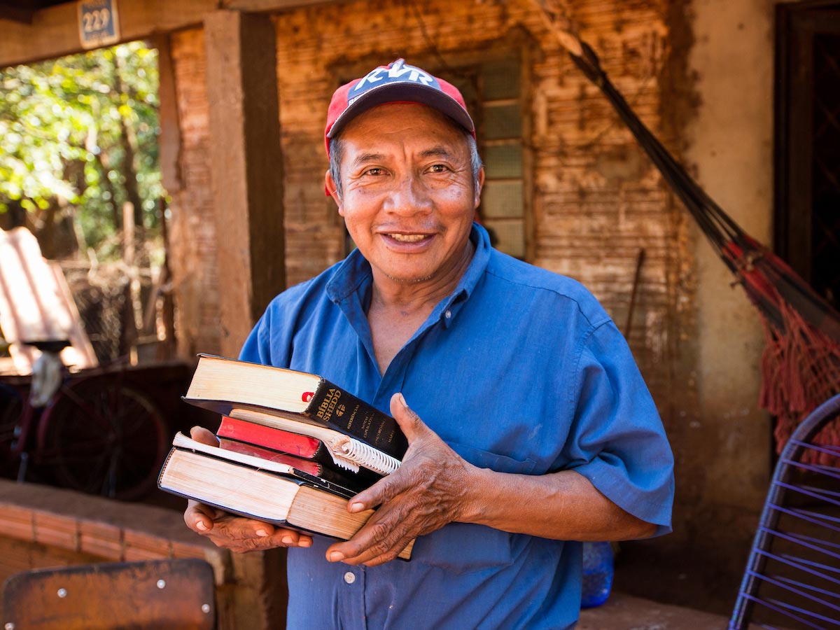 Latino man holding Bibles.